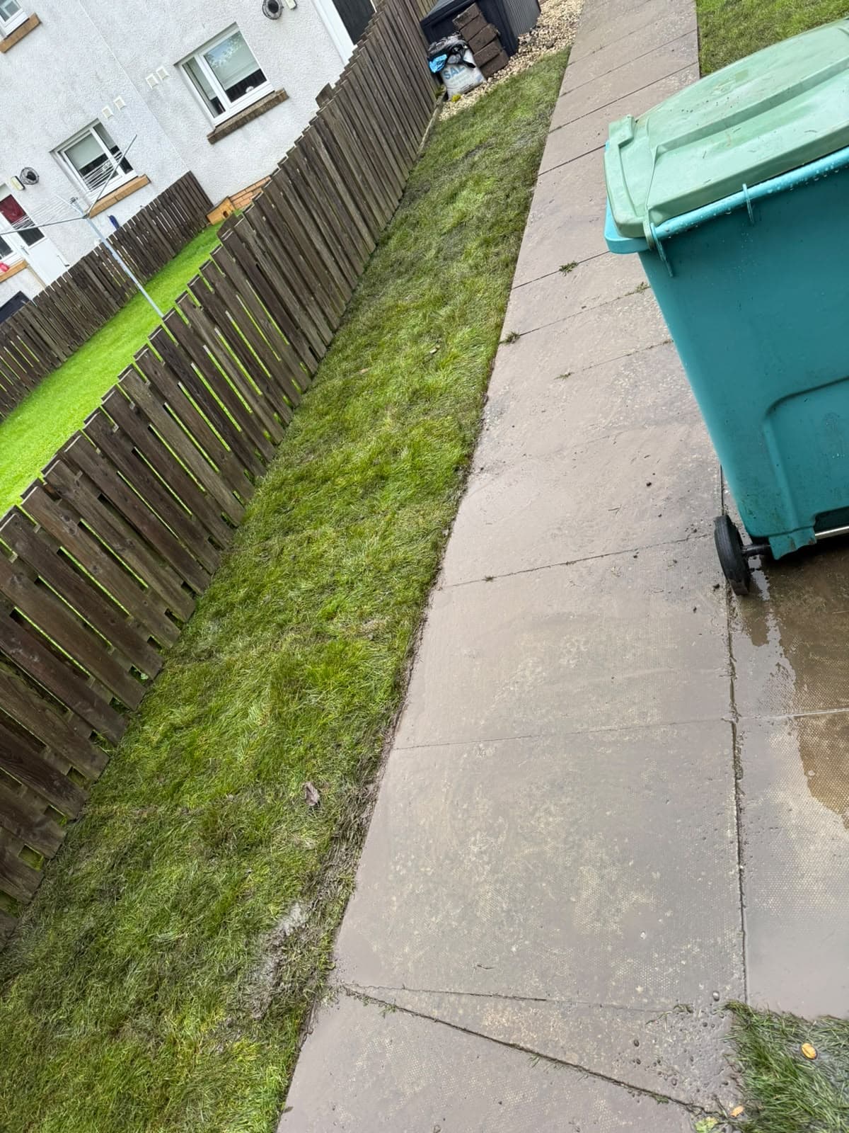 Freshly laid turf running between the fence and the slab path in Chapelhall
