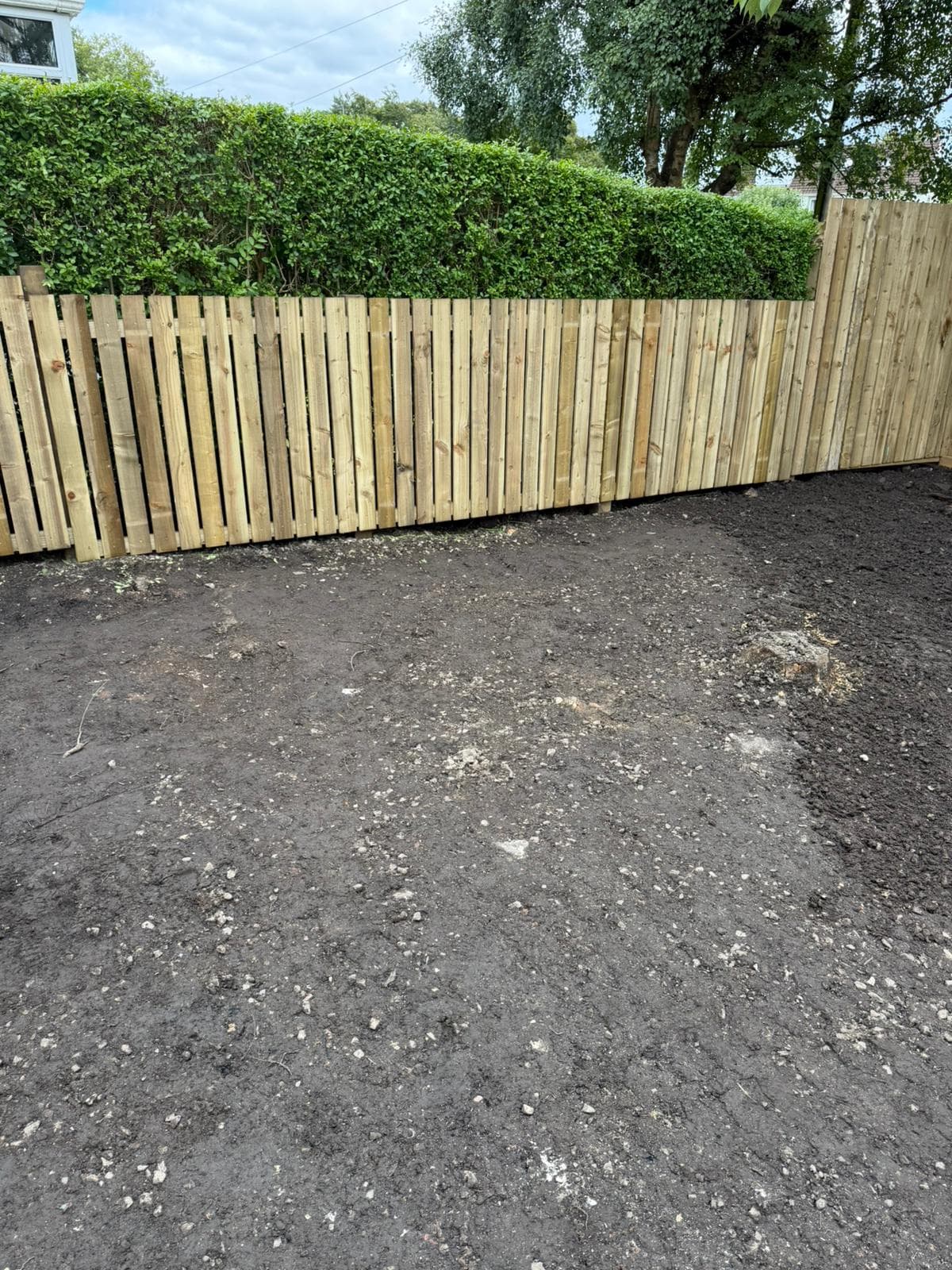 Close-board fence panels and gravel boards being fitted around a rear garden