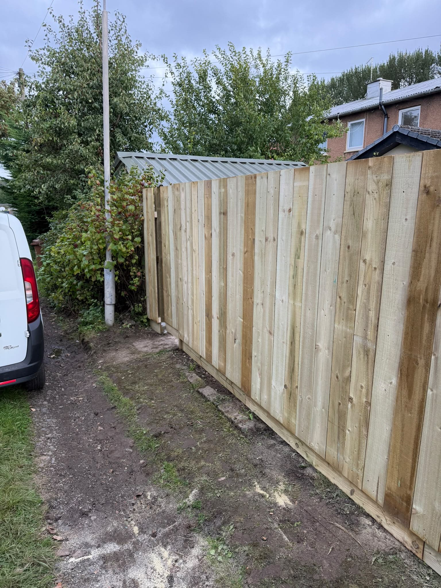 New pressure-treated close-board fence on the same Auldhouse boundary, standing straight with gravel boards along the base