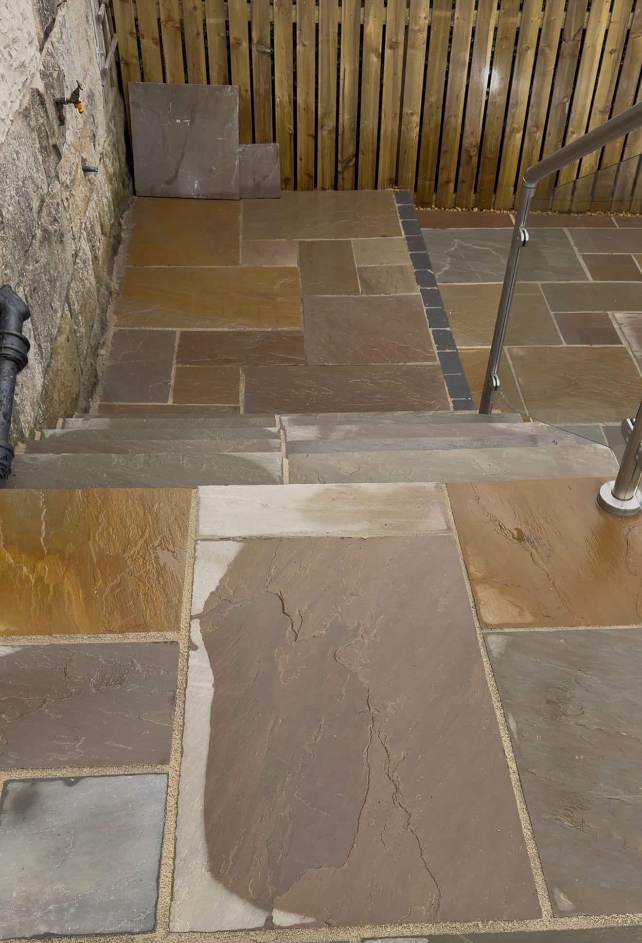 Sandstone steps and glass balustrade detail on a garden patio